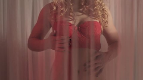 Young woman in red lingerie standing on a bed in flash of red light
