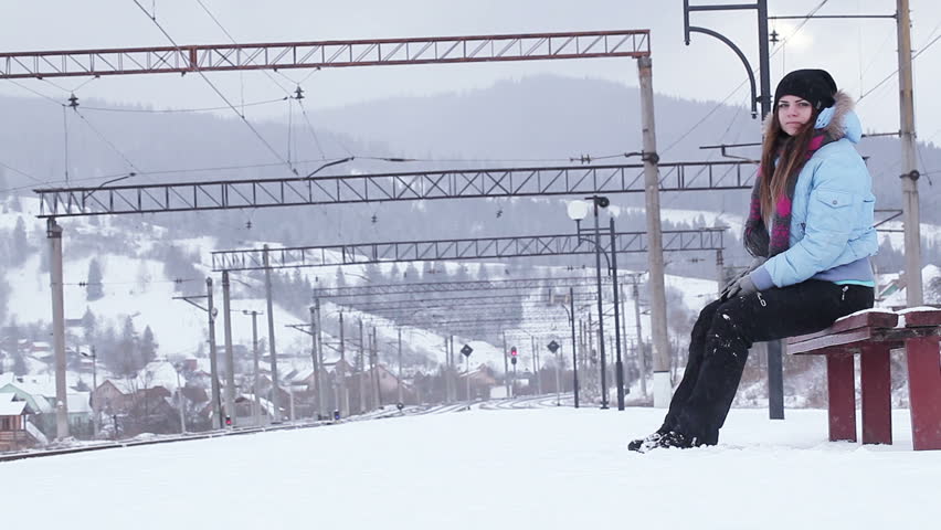 Girl on bench waiting for train in winter
