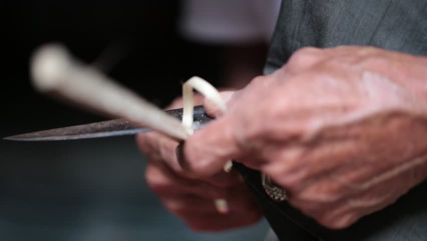 Malaysian kite maker whittling bamboo on kite in his work shop
