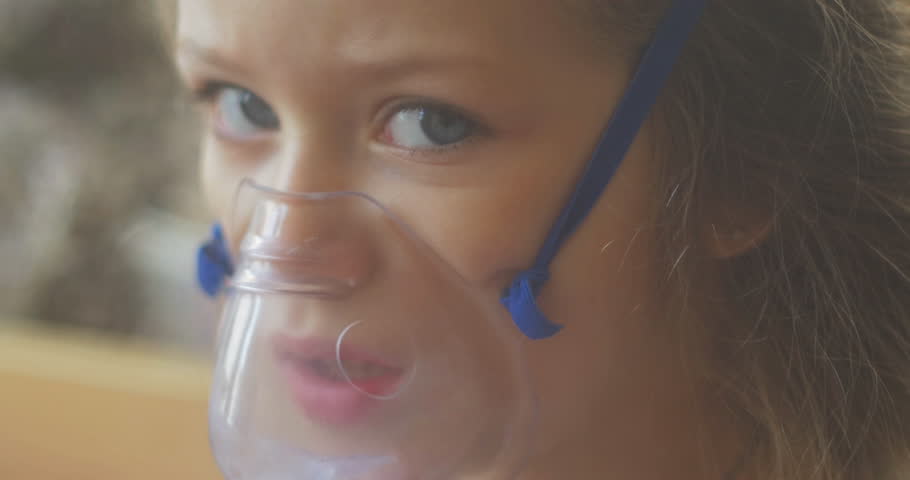 Girl sitting in bed in the hospital and inhales. The girl is sick, coughing, sad, not funny, treatment in the hospital, at the doctor's. Inhalation mask on her face. Royalty-Free Stock Footage #8911852