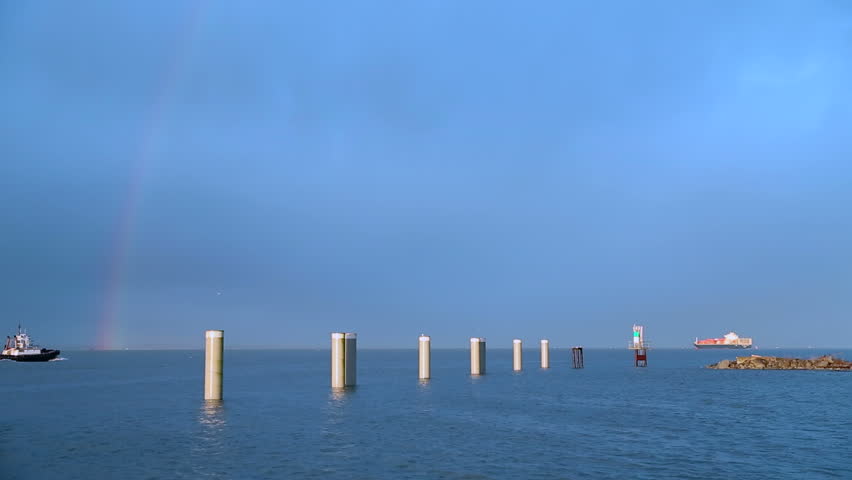 Tugboat and Rainbow, Fraser River. A rainbow curves over the pilings at the mouth of the Fraser River where the river empties into Georgia Strait. Near Vancouver, British Columbia, Canada.