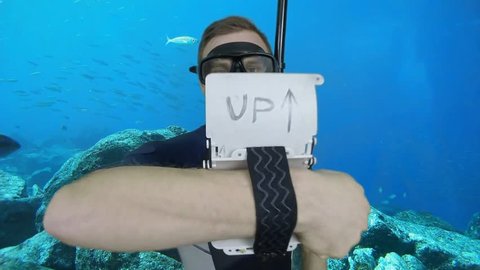 Diving sign- divemaster  writes on the plate and shows ok sign GO UP, ASCENT 1 of 4 also a available on the green screen all of diving signs from course