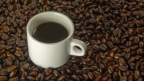 Cup of black coffee rotation on the background of roasted coffee beans 4K