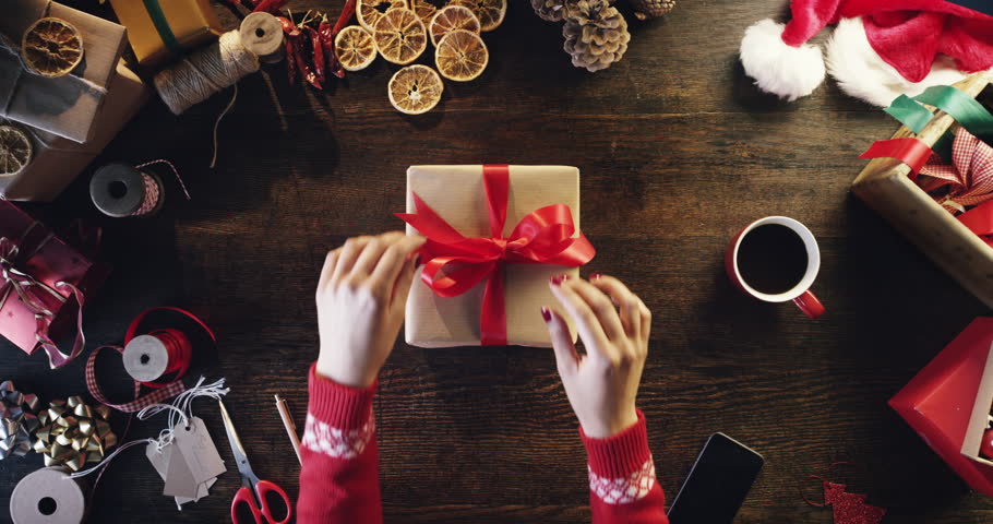 Top view woman unwrapping christmas presents at wooden desk hands from above - Red Epic Dragon