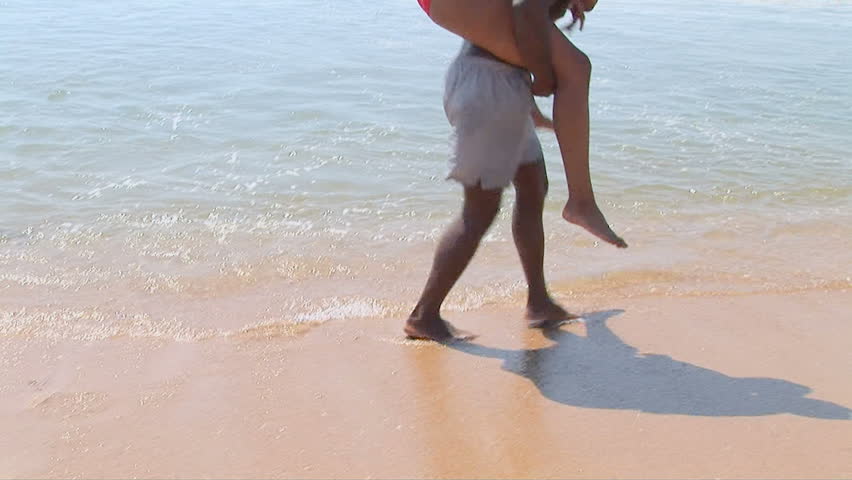 Young African American couple giving piggyback ride at beach	