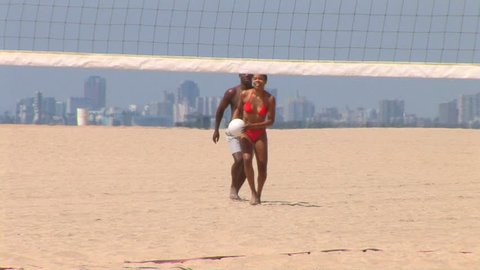 Young African American couple playing volleyball at the beach	