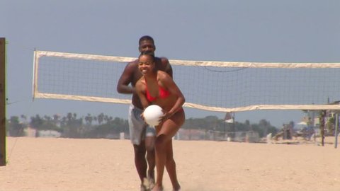 Young African American couple playing volleyball at the beach	