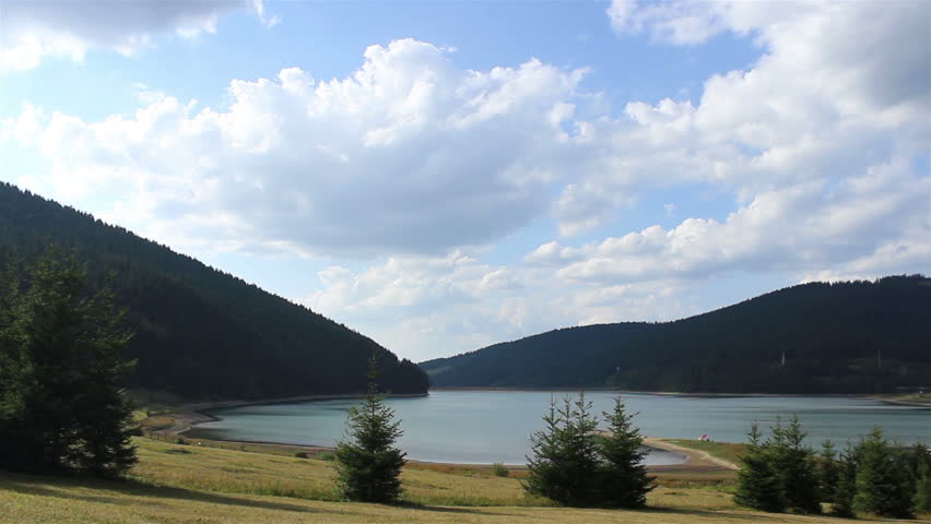 A classic peaceful landscape of lake between conifers  forest, and blue sky in summer day.