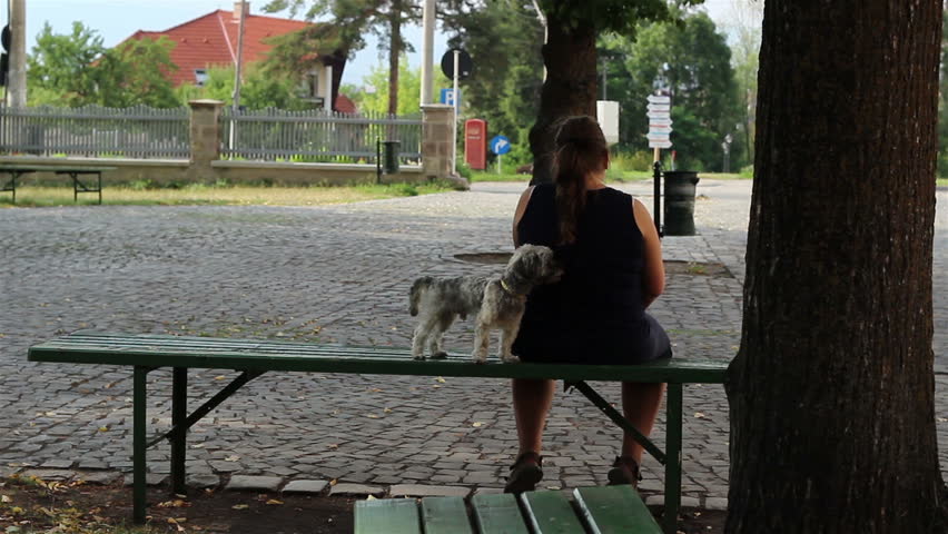 Large woman sitting on a bench with her beloved little  
doggie pet."