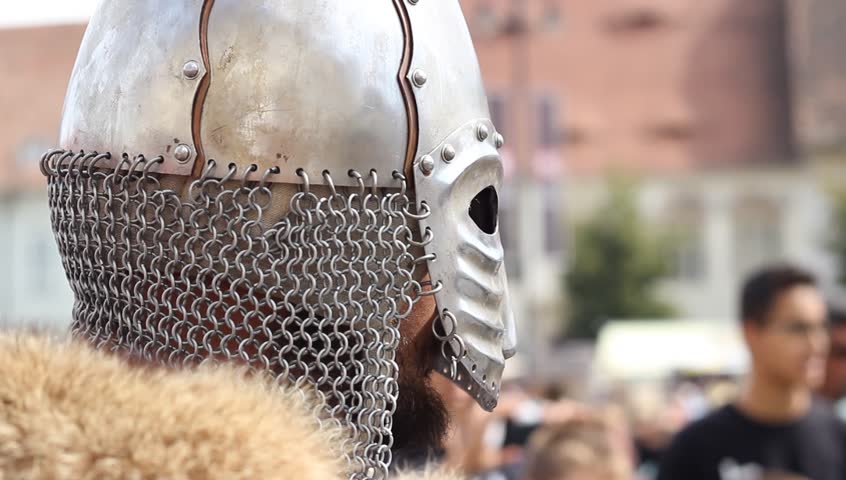 Medieval knight with steel helmet with fur collar looks into the distance.