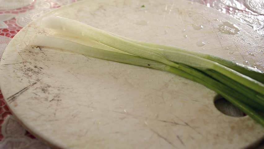Cutting green fresh onion on table. 