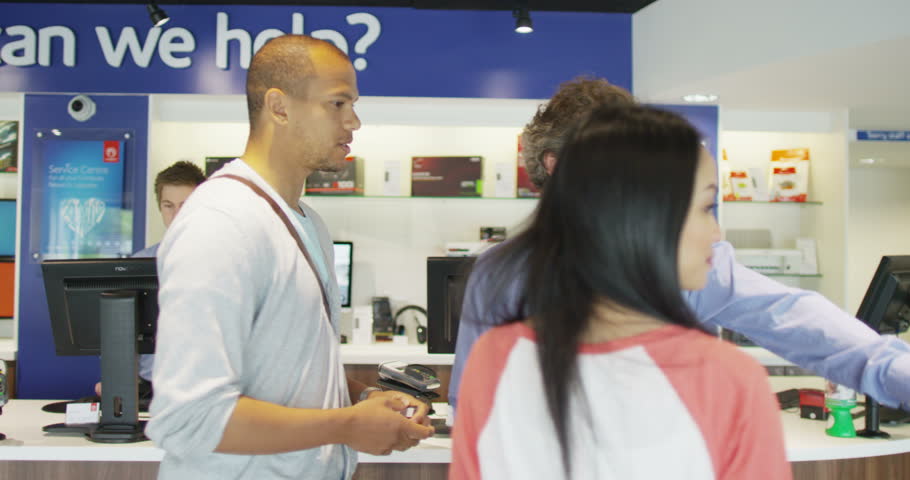 4K Helpful salesman serving customers in consumer electronics store showroom