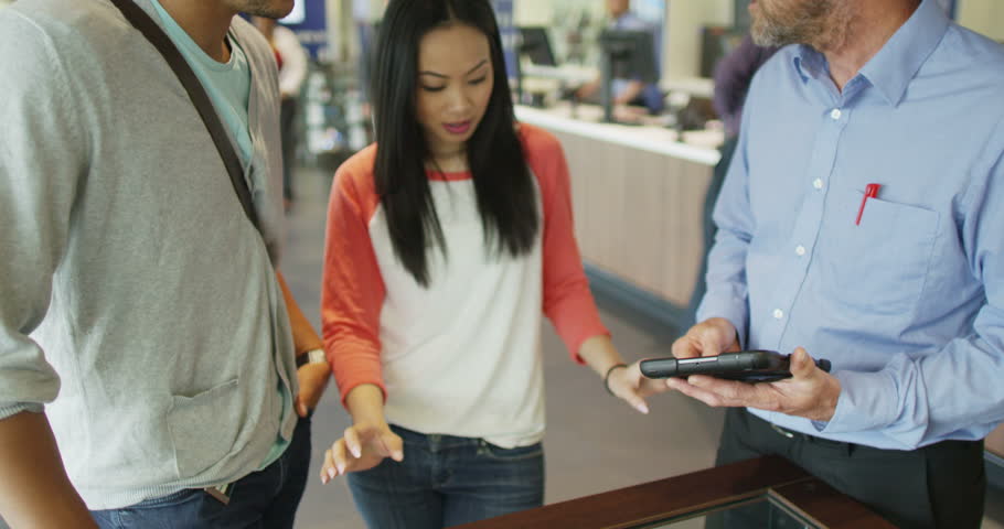 4K Helpful salesman serving customers in consumer electronics store showroom