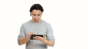 A young and attractive man in his 20s working on a digital tablet with a white background.