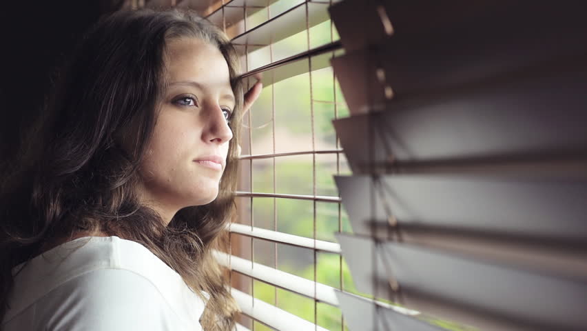Good looking girl looking out of window and smiles