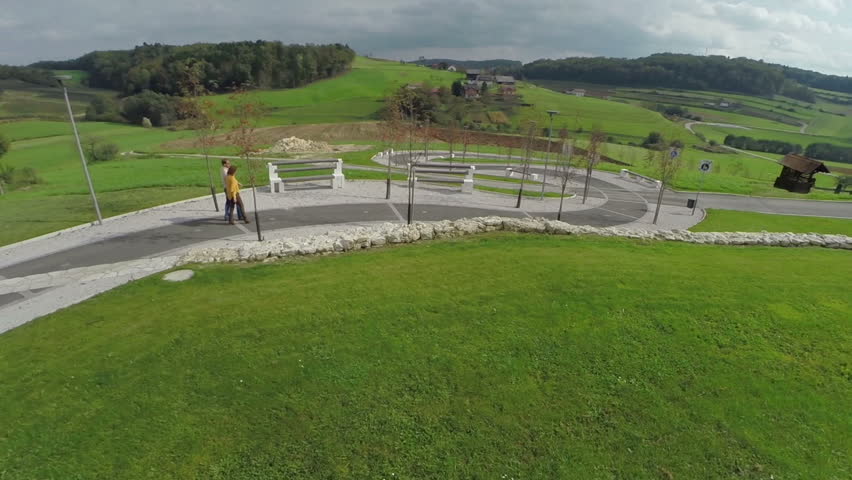 Wrapped paved walkway in the middle of beautiful landscape. Slow motion birds eye view footage is a couple walking on a countryside wrapped paved walkway on a sunny day.