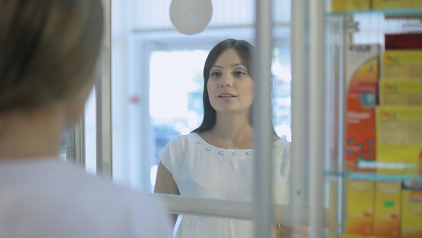 Pharmacist talking to a girl at the pharmacy through the shop window