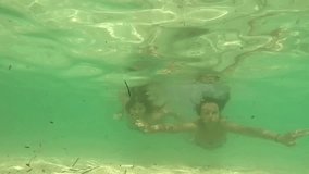 Young female friends having fun together underwater and waving to the camera. slow motion stock video