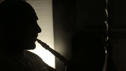 SLOW MOTION: Shadow of a man smoking a hookah.