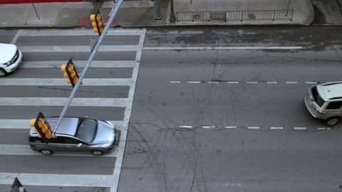 View of cars slowly cruising through a crosswalk, in a city during the day.