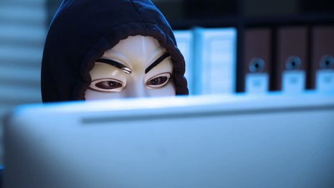 MOSCOW, RUSSIA - FEBRUARY 25, 2015:  The hacker in a mask of Guy Fawkes uses the computer late at night. Close up. Dolly shot.