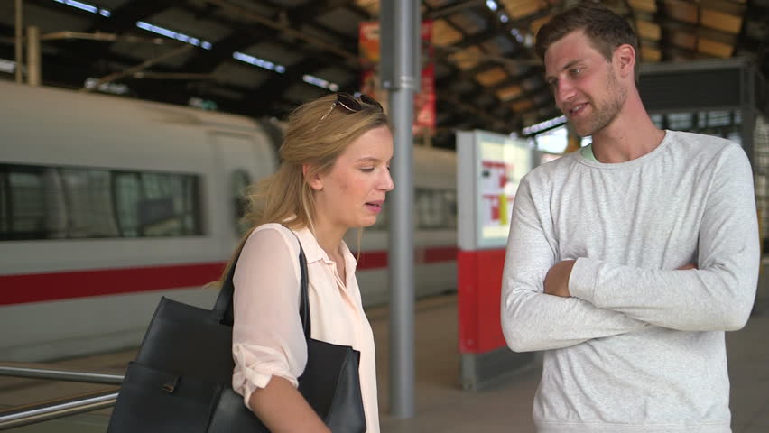 young adult couple talking waiting for train on trainstation