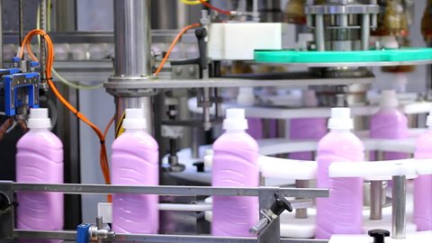 Bottle filling machine. Bottles of fabric softener moving along a conveyor belt.
Cleaning products. Chemical industry. Industrial production line.