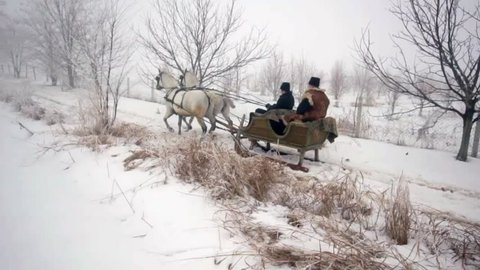 Old father and his son having a ride in sledge pulled by horses