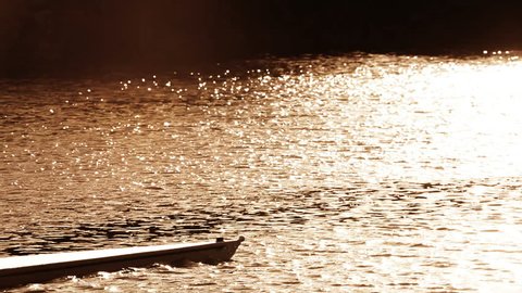 Oarsmen in training on the water at sunrise, seen in silhouette