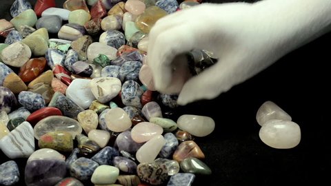 From mixed semiprecious stones in bulk, womans hands are choosing rose quartz only