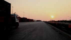 Stock Video Footage 1920x1080 Truck Sunset Container Cargo. Truck transports container rides into the sunset. Delivery of goods, cargo. Large port, transportation of container against the sunset.