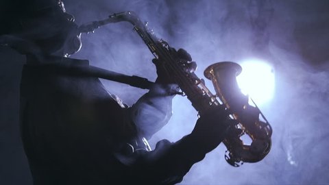 African man colored old black playing saxophone dark background music backlit silhouette