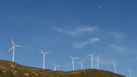 The moon shines over a wind farm comprising ten turbines