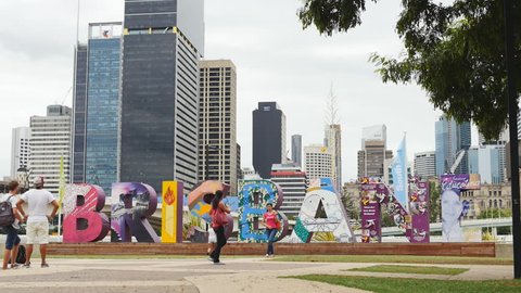 Photograph pose next to huge Brisbane sign, slow motion dolly. Brisbane, Queensland, Australia. Jan 2015.