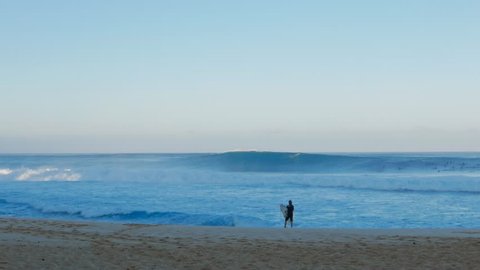 a surfer watches pipeline and waits before paddling out