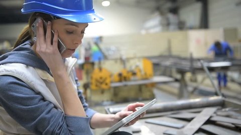 Woman engineer in factory talking on mobile phone