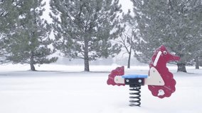Toy Horse in playground  surrounded by pine trees under snow at park during winter season.