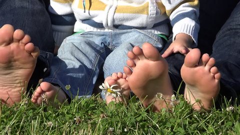 Little child and parents soles. Family bare feet on green grass. daisy flower