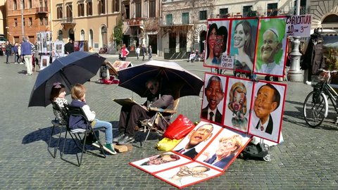 ROME, ITALY - FEBRUARY 2015 - Man painting caricature of children, tourists in Piazza Navona. Stall selling paintings of celebrities. Rome, Roma, Italy, Italia. 4k, UHD, Ultra HD, UltraHD