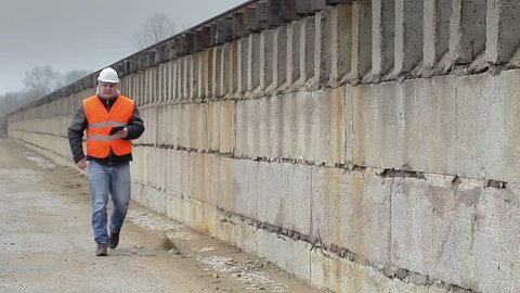 Engineer with tablet PC walking near the concrete wall