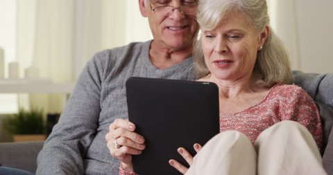 Beautiful senior couple using tablet on couch
