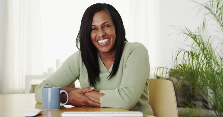 Happy laughing senior black woman sitting at desk | Shutterstock HD Video #9062933