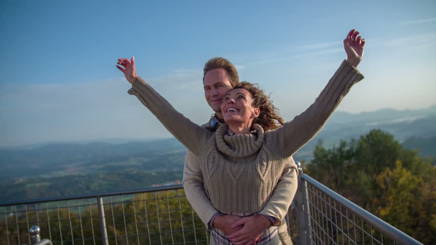 Couple stretching hands to feel like flaying. Slow motion close up footage of a couple standing on top of a tower with beautiful view and stretching there hand to feel like flaying on windy day.