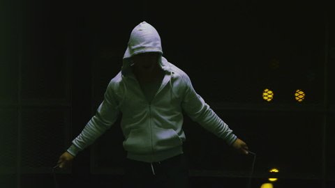 4K Slow motion hooded male athlete skipping at night with a jump rope in urban setting, shot on RED EPIC