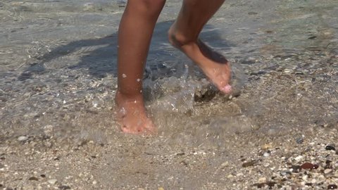 4K Close up View of Barefoot Child Playing on Beach in Waves, Sea Water on Seashore, Happy Little Girl Having Fun Jumping, Spinning on a Sandy, Coastline, Seaside, Children in Summer Vacation Closeup