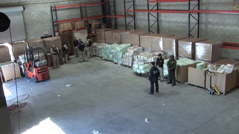 CIRCA 2010s - DEA agents guard confiscated drugs in a warehouse.