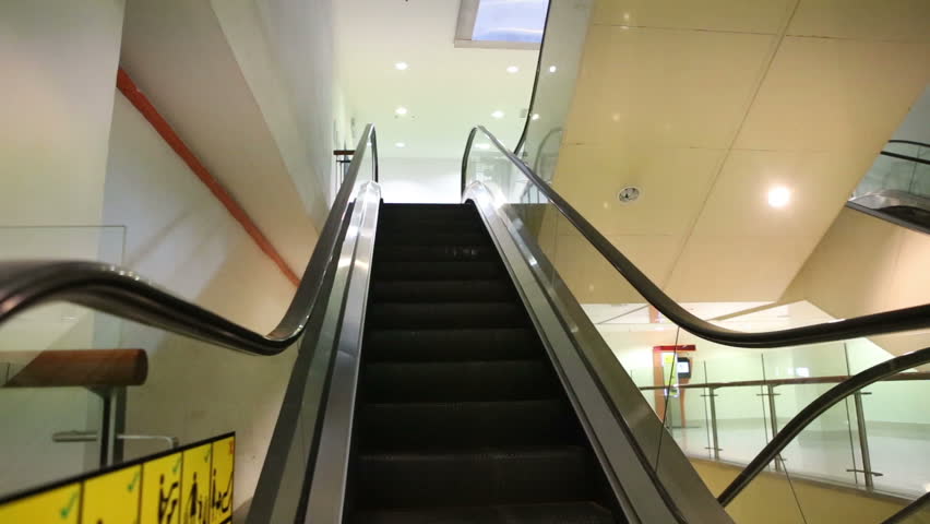 young mother and small blonde daughter get down the escalator in trade center