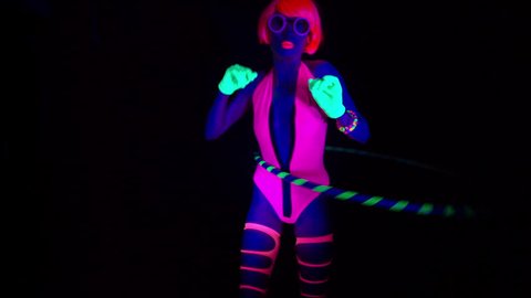 sexy female disco dancer poses in UV costume with hulahoop