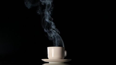 White cup with very much hot smoking black coffee on dark background