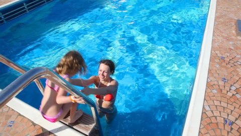 happy woman and little girl having fun in swimming pool on cruiser